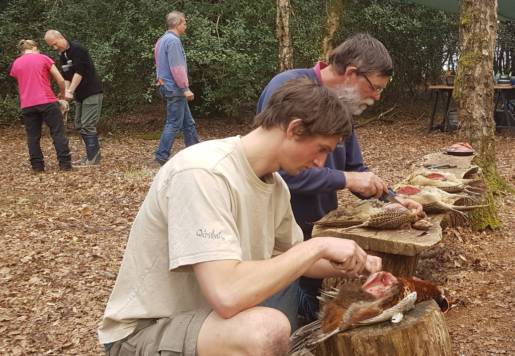Two men preparing game in the woods at their Bushcraft experience