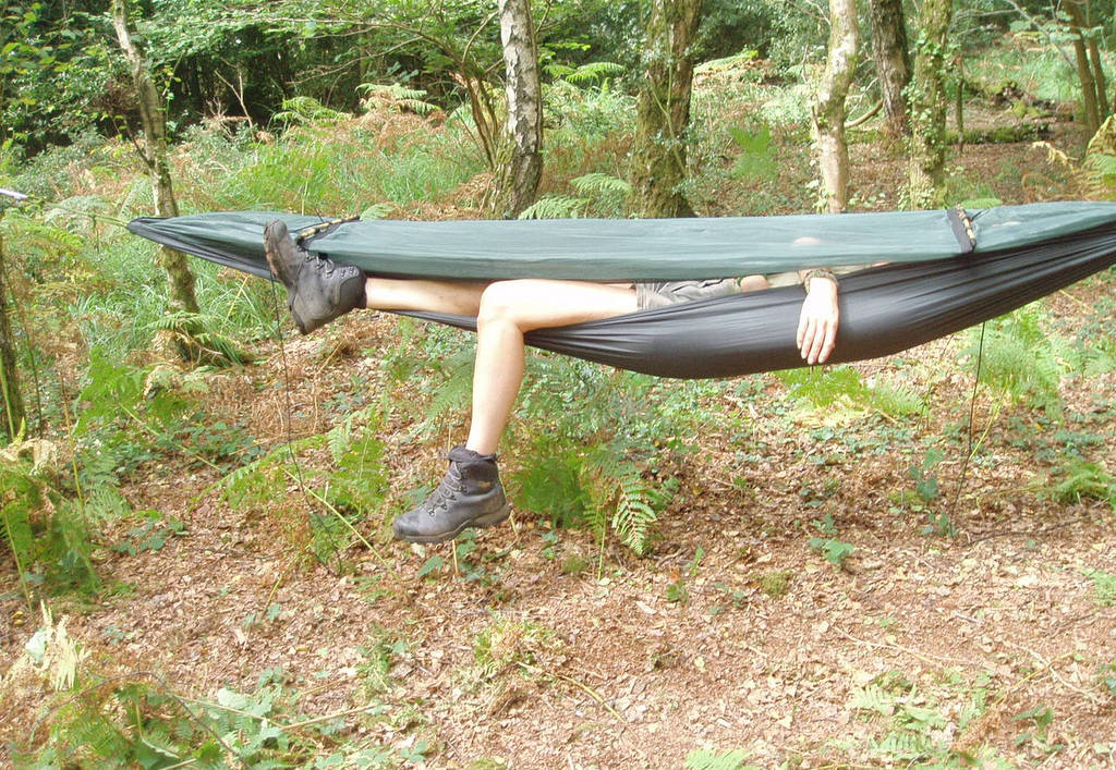 A man asleep in a hammock in the woods.