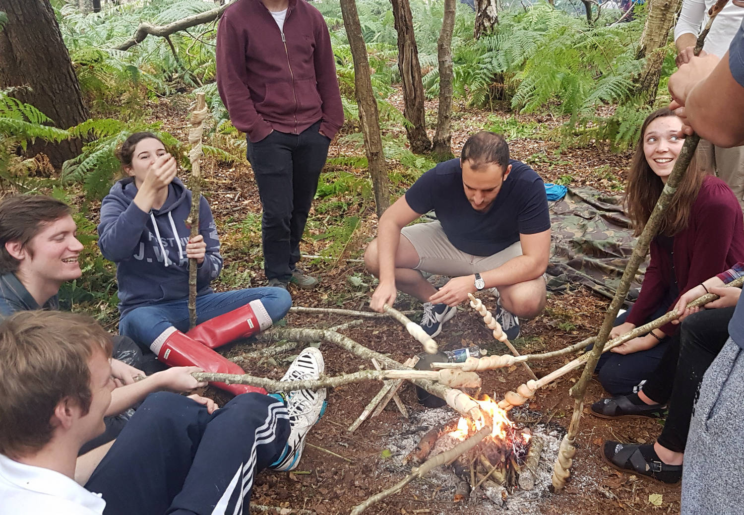 A group of people cooking over a campfire in the woods