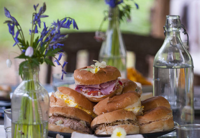 A photograph of sandwiches on a plate surrounded by flowers.
