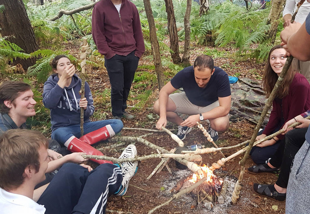 A group around a campfire making bread