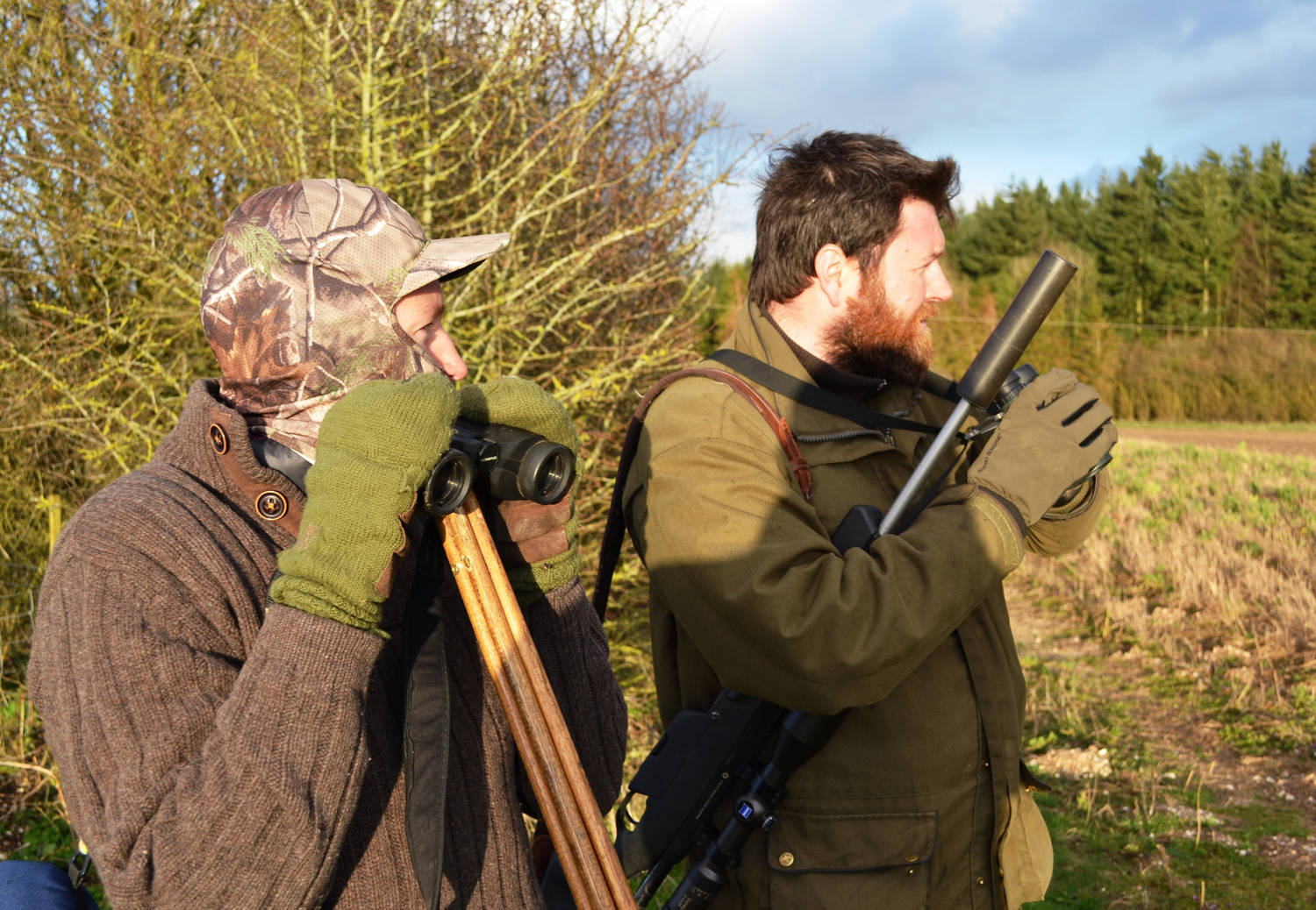  A photograph of two men stood in a field with hunting equipment